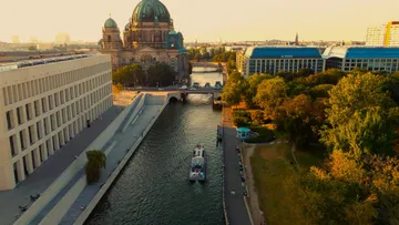 River boat travels near cathedral in cityscape.