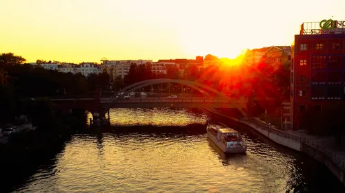 Boot auf Fluss unter sonnenuntergangsbeleuchteter Brücke.