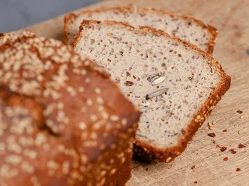 Sliced bread on wooden board with seeds.