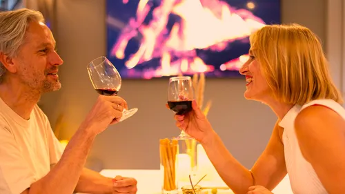 Couple toasting with wine glasses at dinner.