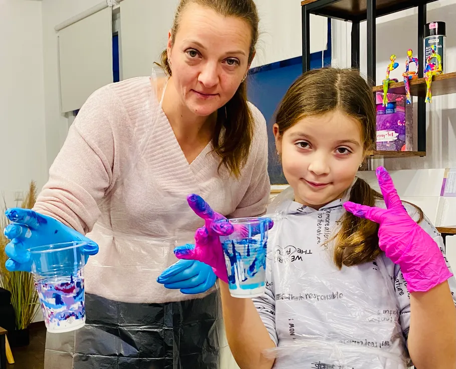 Two people holding paint cups indoors.