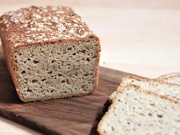 Bread on wooden board, cut a few slices next to it.