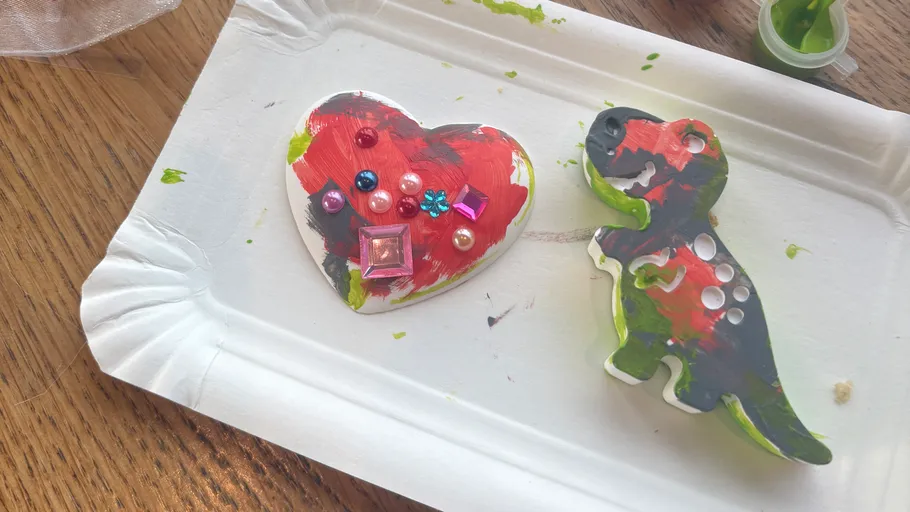 Painted dinosaur and heart with gems on tray.