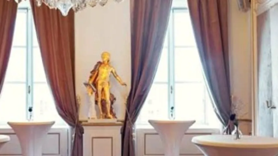 Golden statue between elegant draped windows.