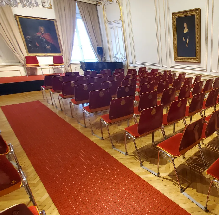 Leerer Raum mit roten Stühlen und Gemälden.