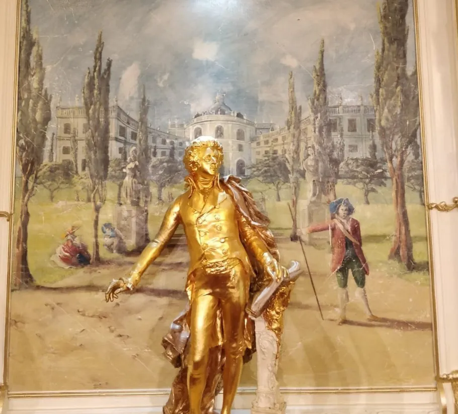 Goldene Statue eines Mannes vor Gemälde.