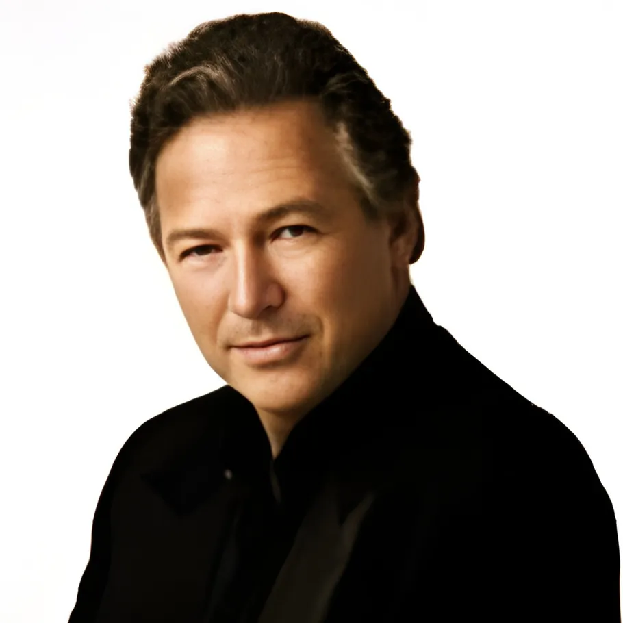 Mann in schwarzem Hemd vor weißem Hintergrund.