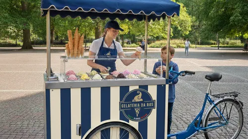 Eisverkäuferin bedient Kind im Park.