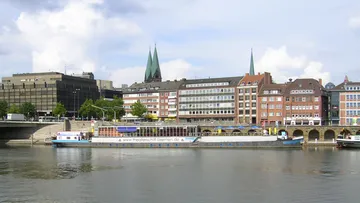 Boot neben Gebäuden an einem Fluss angedockt.