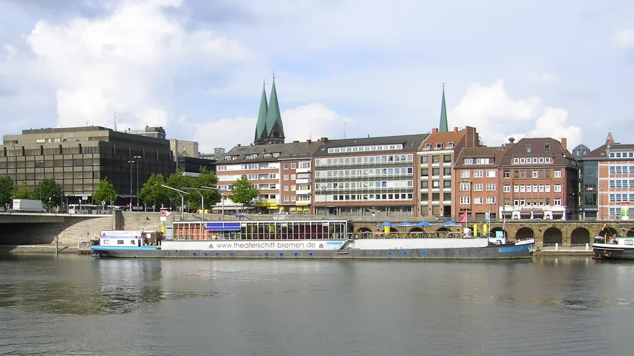 Boat docked by buildings along a river.