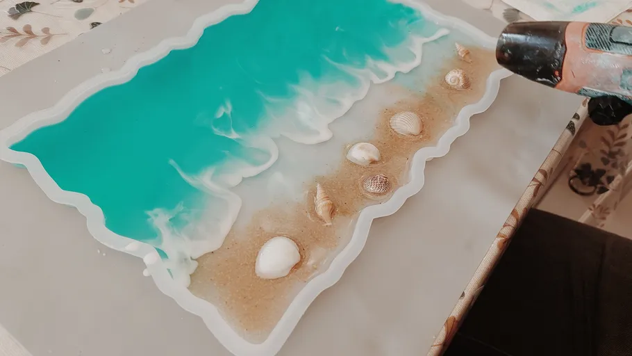Resin ocean art with seashells on table.