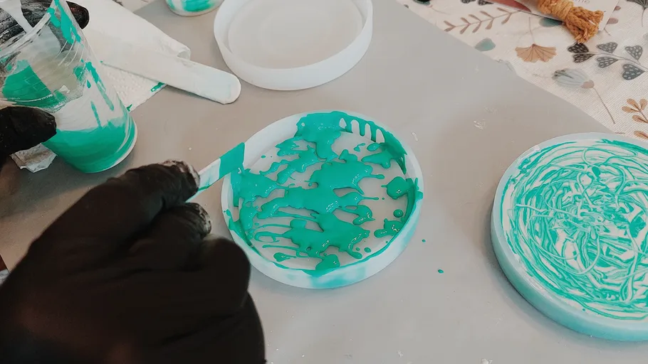 Person pouring blue resin into a mold.