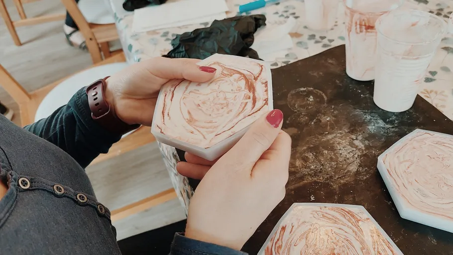 Person holding handcrafted hexagonal coaster indoors.