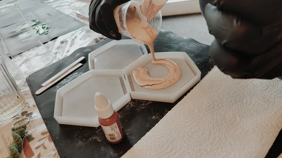 Person pouring resin into hexagonal molds.