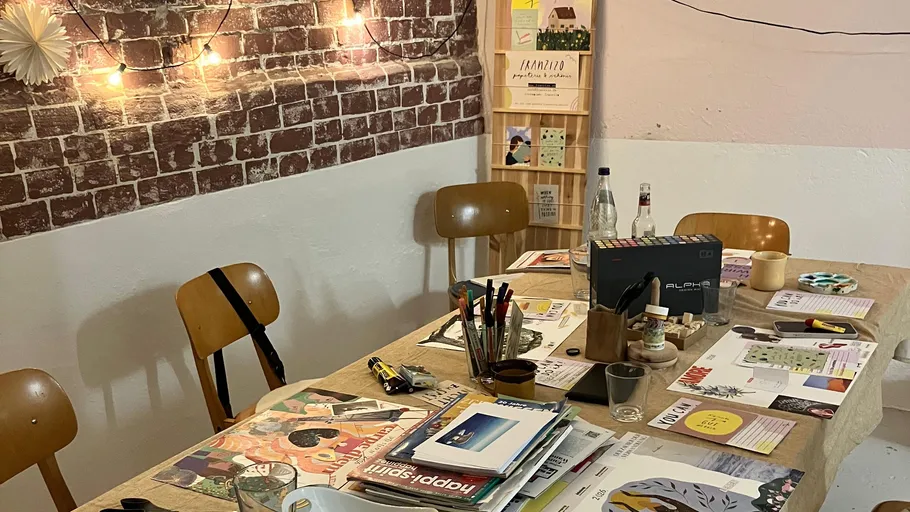 Art supplies on wooden table, brick wall background.