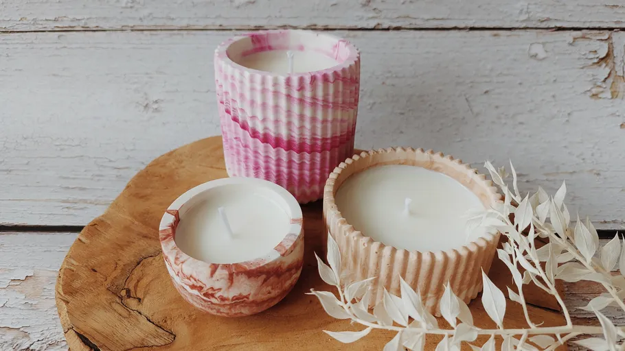 Three decorative candles on wooden tray.