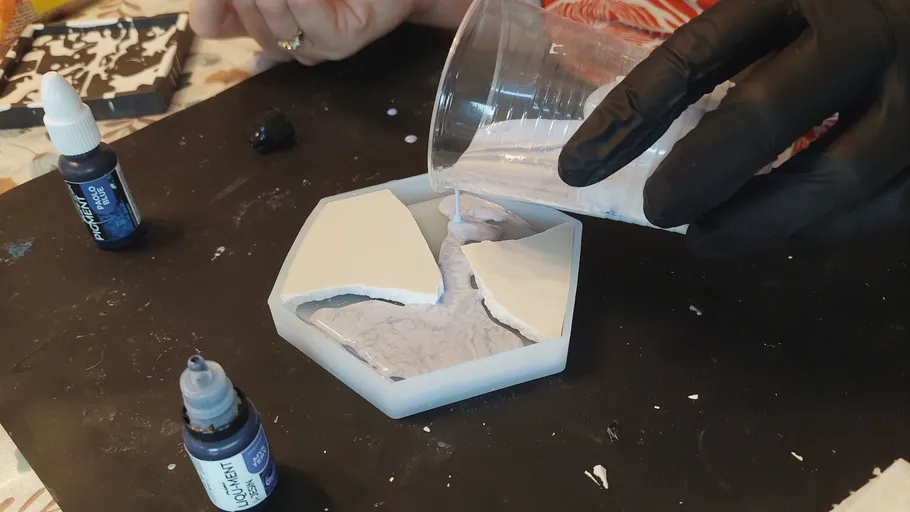 Person pouring liquid into hexagonal mold.