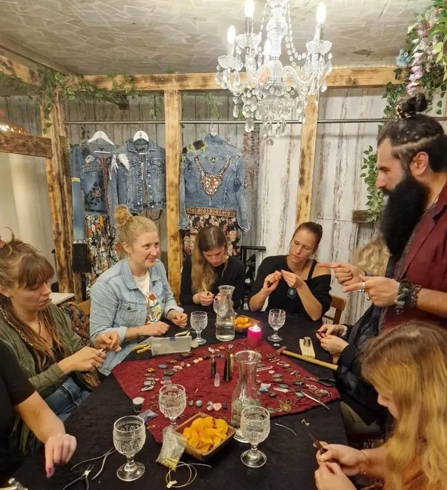 People crafting jewelry around table in cozy room.