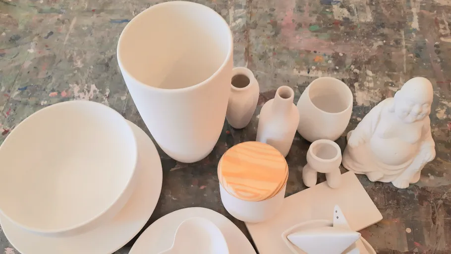 White ceramics on a colorful studio table.