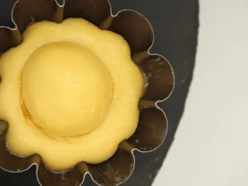 Yellow mold has a round filling in a baking pan.