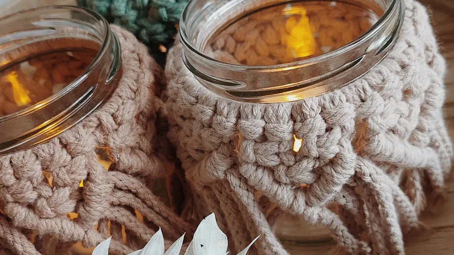 Glasgläser mit Häkelüberzügen und Kerzen innen.