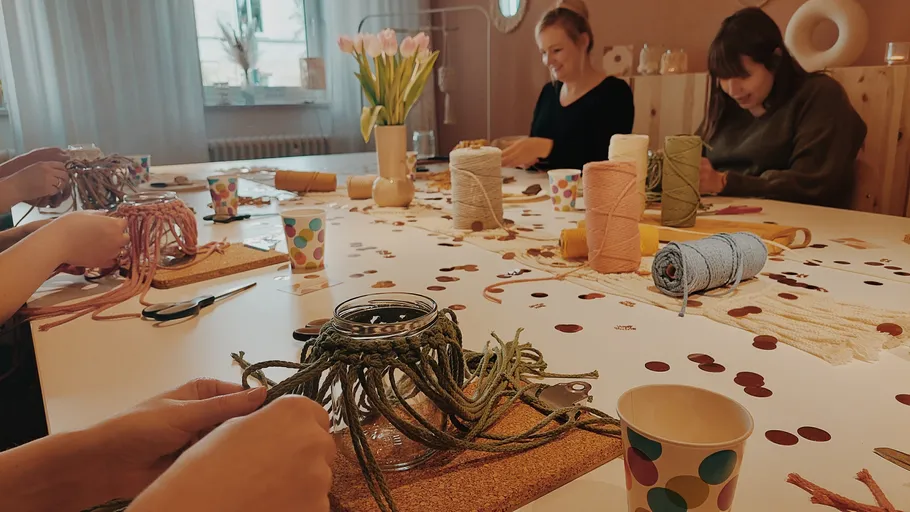 Leute machen Makramee-Handwerk am Tisch.