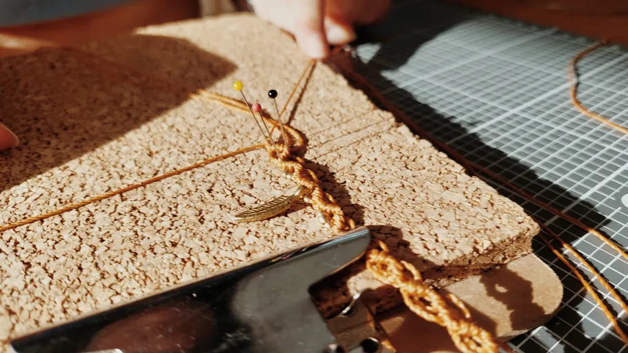 Makramee-Knoten auf Korkplatte mit Nadeln.