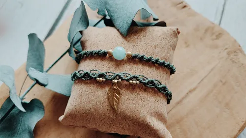 Zwei geflochtene Armbänder auf einem Kissen.