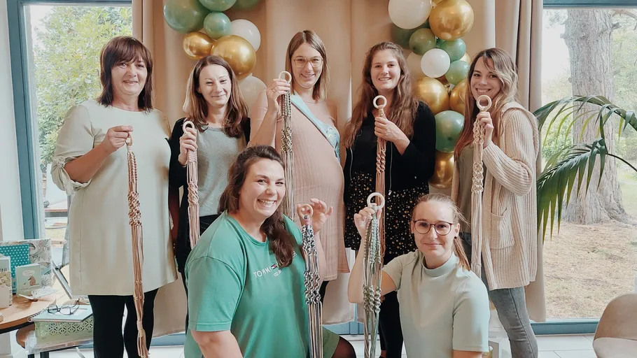 Group of women holding macrame ropes indoors.