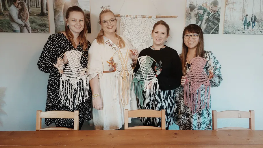 Vier Frauen halten handgemachte Makramé-Dekorationen drinnen.