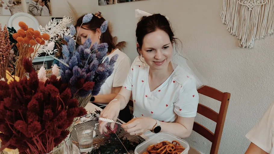 Frau bastelt mit Blumen am Tisch.