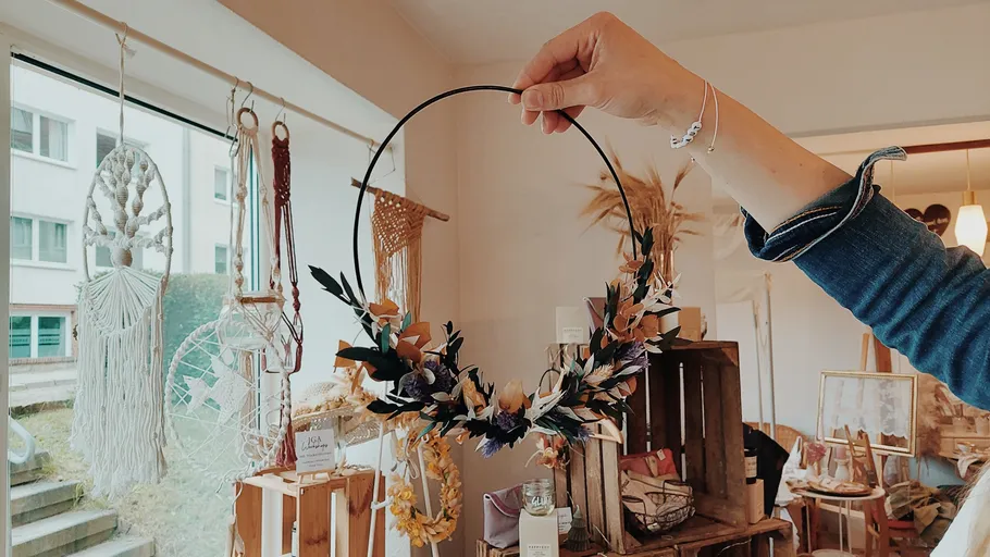 Hand hält Blumenkranz im Bastelladen.