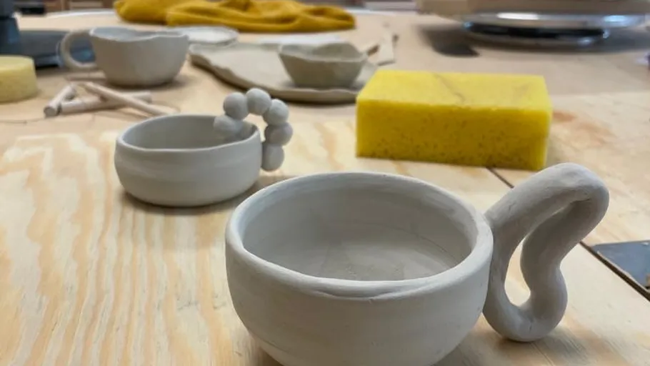 Ungebrannte Tonbecher auf einem Holztisch.