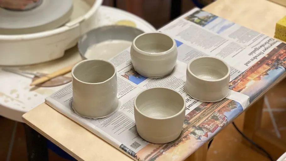 Four clay cups drying on newspaper.