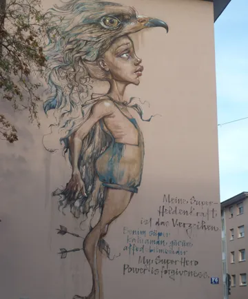 Mural of a person with eagle head on building wall.
