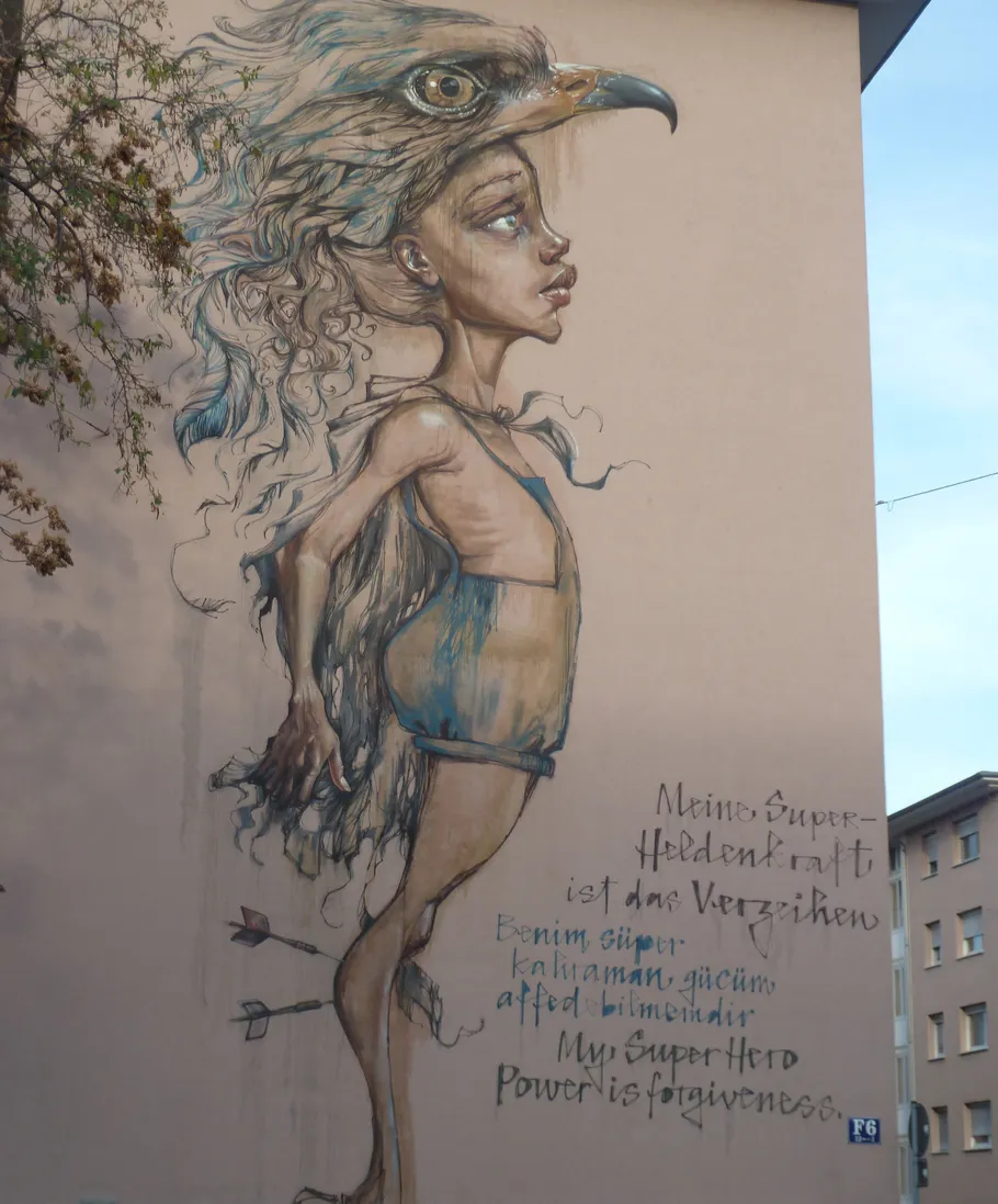 Mural of a person with eagle head on building wall.