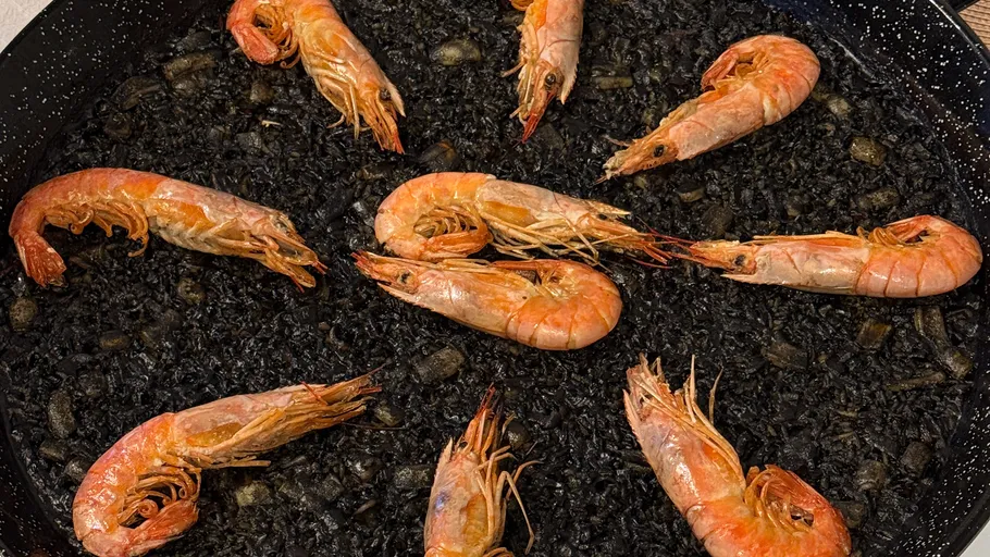 Garnelen auf schwarzem Reis in einer Pfanne.