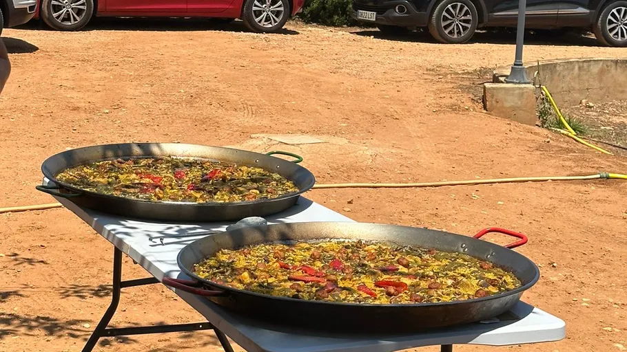 Two large paellas on outdoor table.