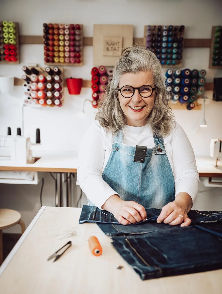 Woman sewing in workshop with thread spools.
