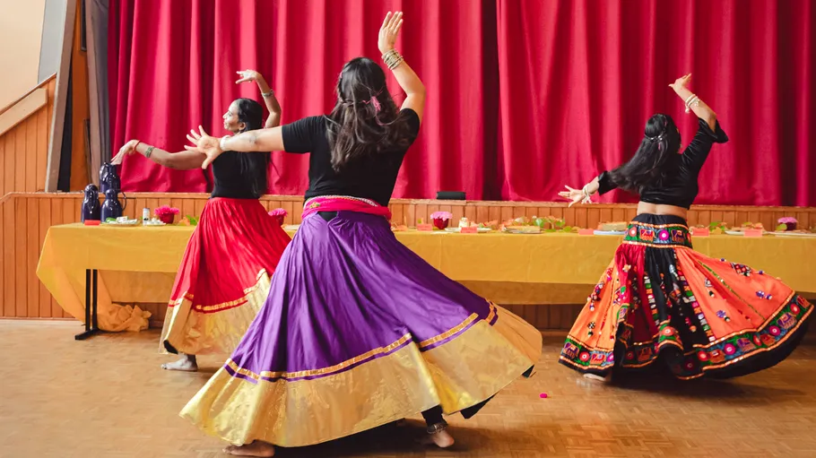 Women dancing in colorful dresses indoors.