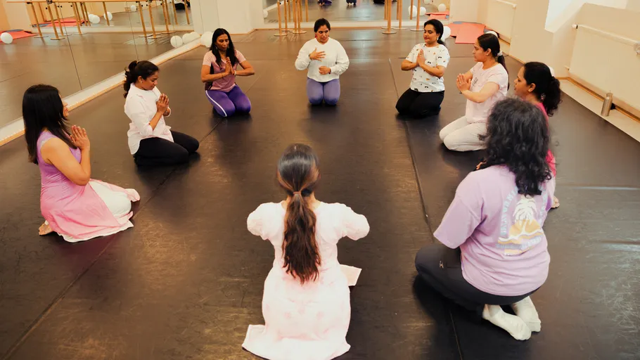 Women in yoga poses on studio floor.