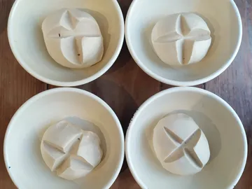 Four shaped dough pieces lie in white bowls.
