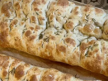 Loaf of bread with rosemary on wooden board. Freshly baked.