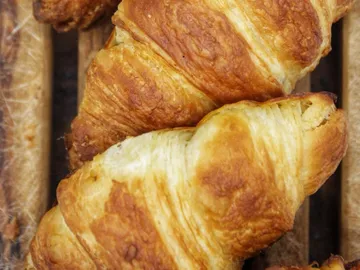Croissants are freshly baked on a wooden table.