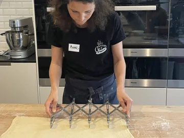 Woman uses a tool to roll out dough in the kitchen.