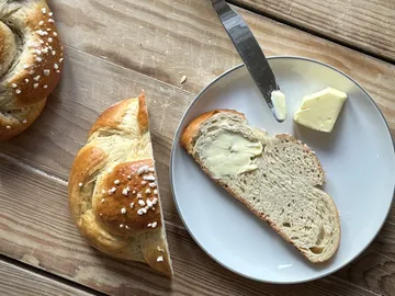 Ein Brötchen wird mit Butter auf einem Teller serviert.