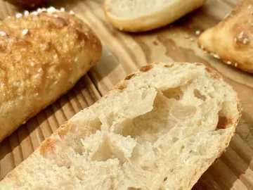 The piece of bread lies on a wooden board, the interior is soft and airy.