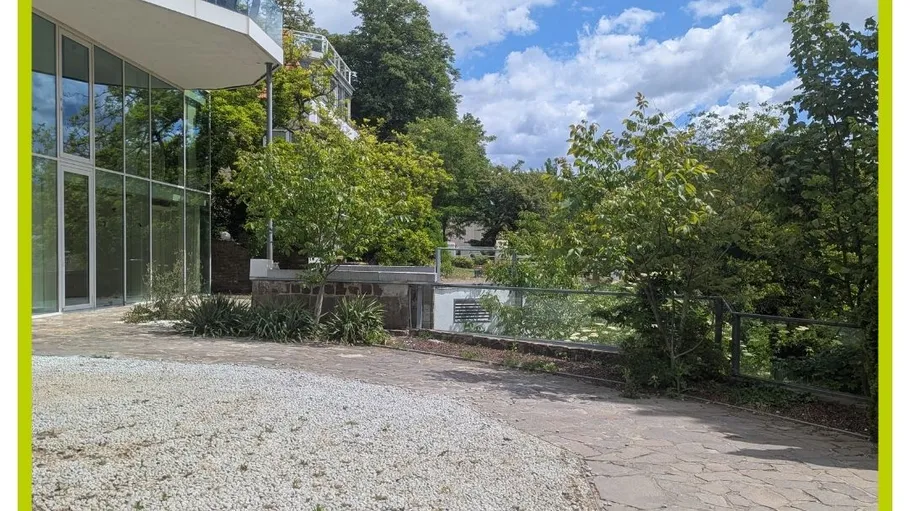 Building exterior with glass walls and surrounding trees.