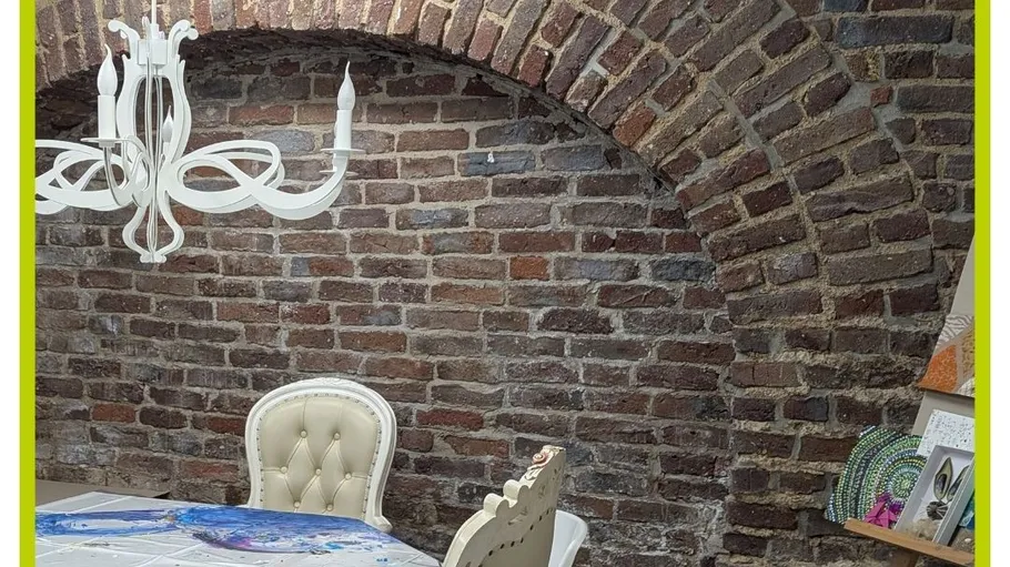 Essbereich mit Backsteinbogen im Hintergrund.