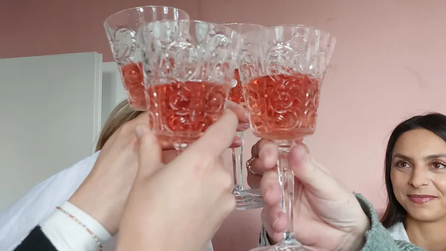 People toasting with rose wine glasses indoors.